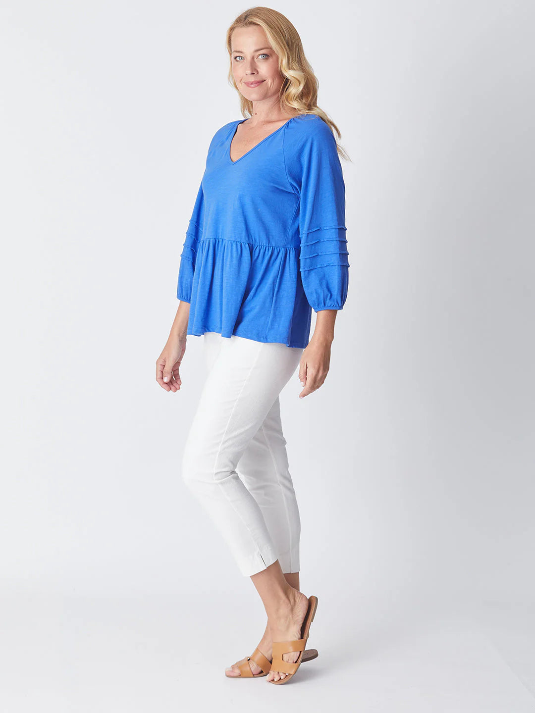 Woman wearing a blue top and white pants on a white background
