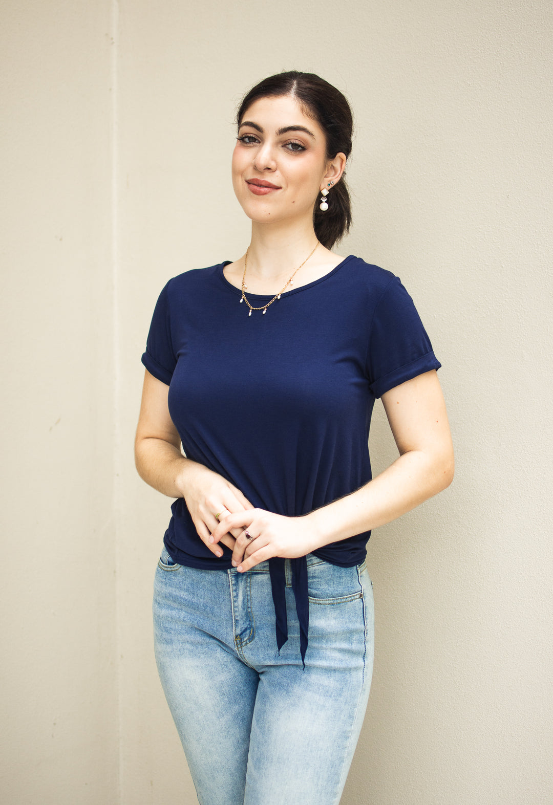 Woman wearing navy modal tee with cuffed sleeves and tie-front detail, styled with light denim jeans — breathable summer top.