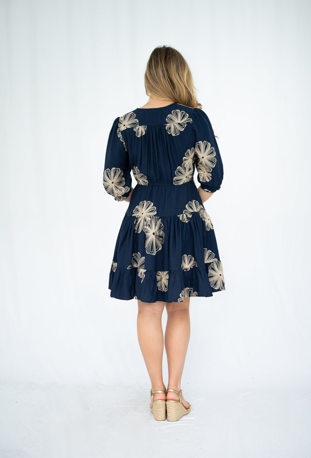 Woman wearing a navy dress with floral patterns on a white background