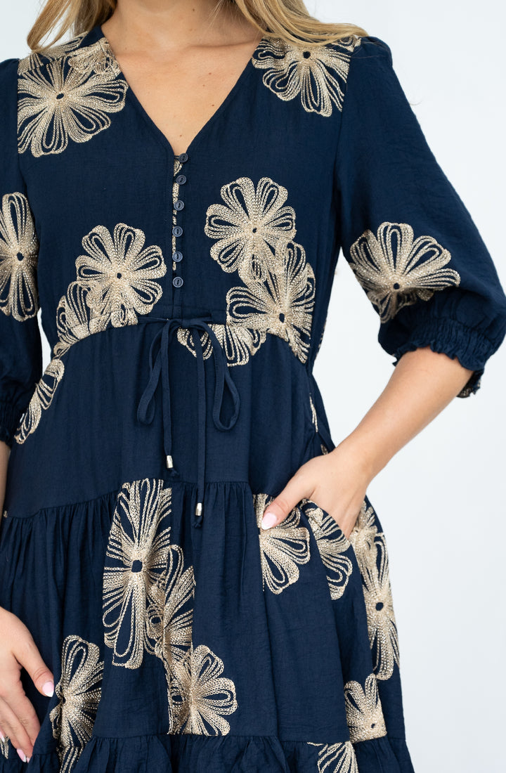 Navy blue dress with gold floral embroidery on a white background