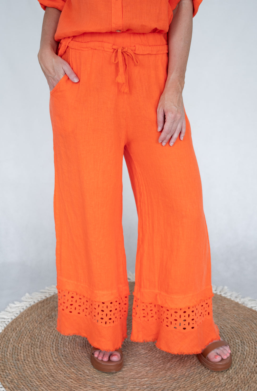Person wearing bright orange pants with a white background