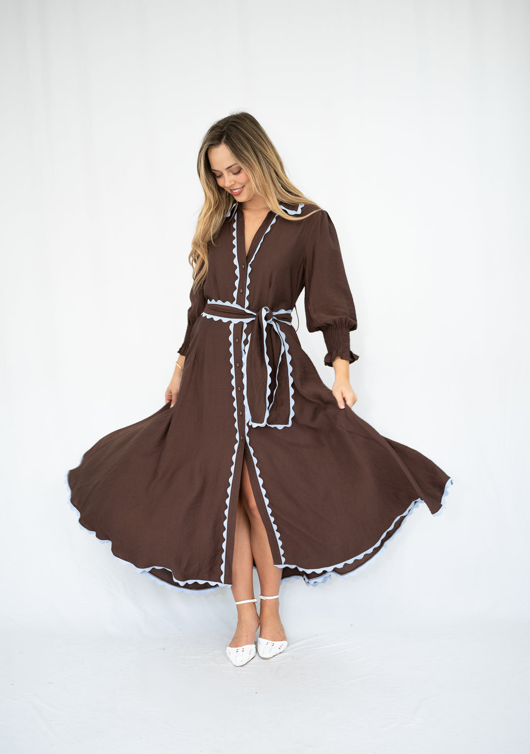 Woman wearing a brown dress with white trim on a white background