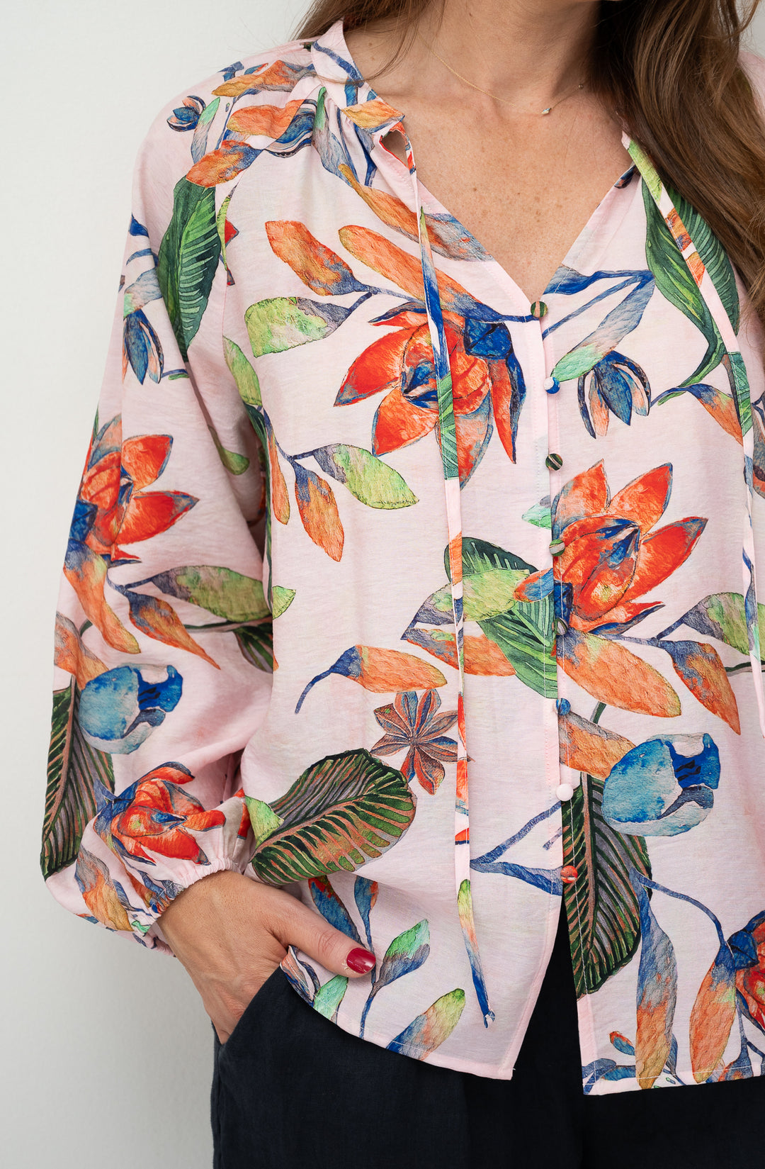 Colorful floral patterned blouse worn by a person on a white background