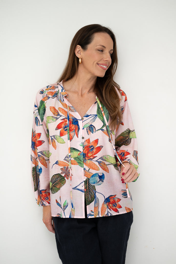 Woman wearing a colorful floral blouse against a white background